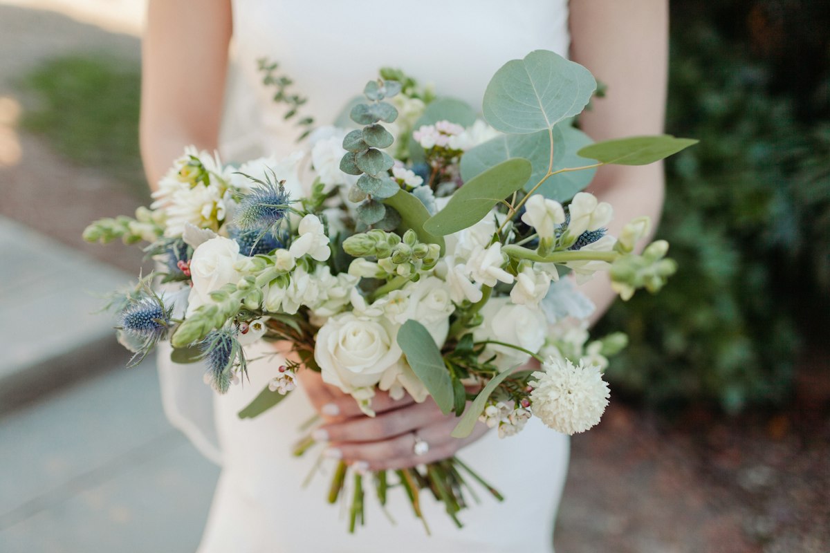 Sposa che tiene un bouquet di fiori bianchi e verdi