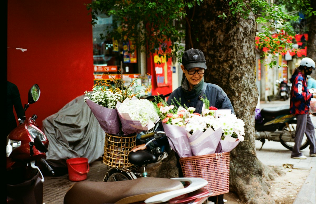 Fiorista che sistema mazzi di fiori su una bicicletta in città