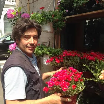 Luca con un vaso di fiori rossi davanti al negozio